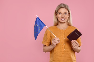Photo of Immigration. Happy woman with passport and flag of European Union on pink background, space for text