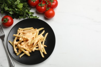 Photo of Delicious French fries with cheese sauce, tomatoes, dill and parsley on white marble table, flat lay. Space for text