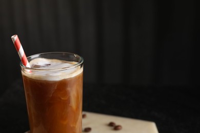 Photo of Refreshing iced coffee with milk in glass on table against dark gray background, closeup. Space for text
