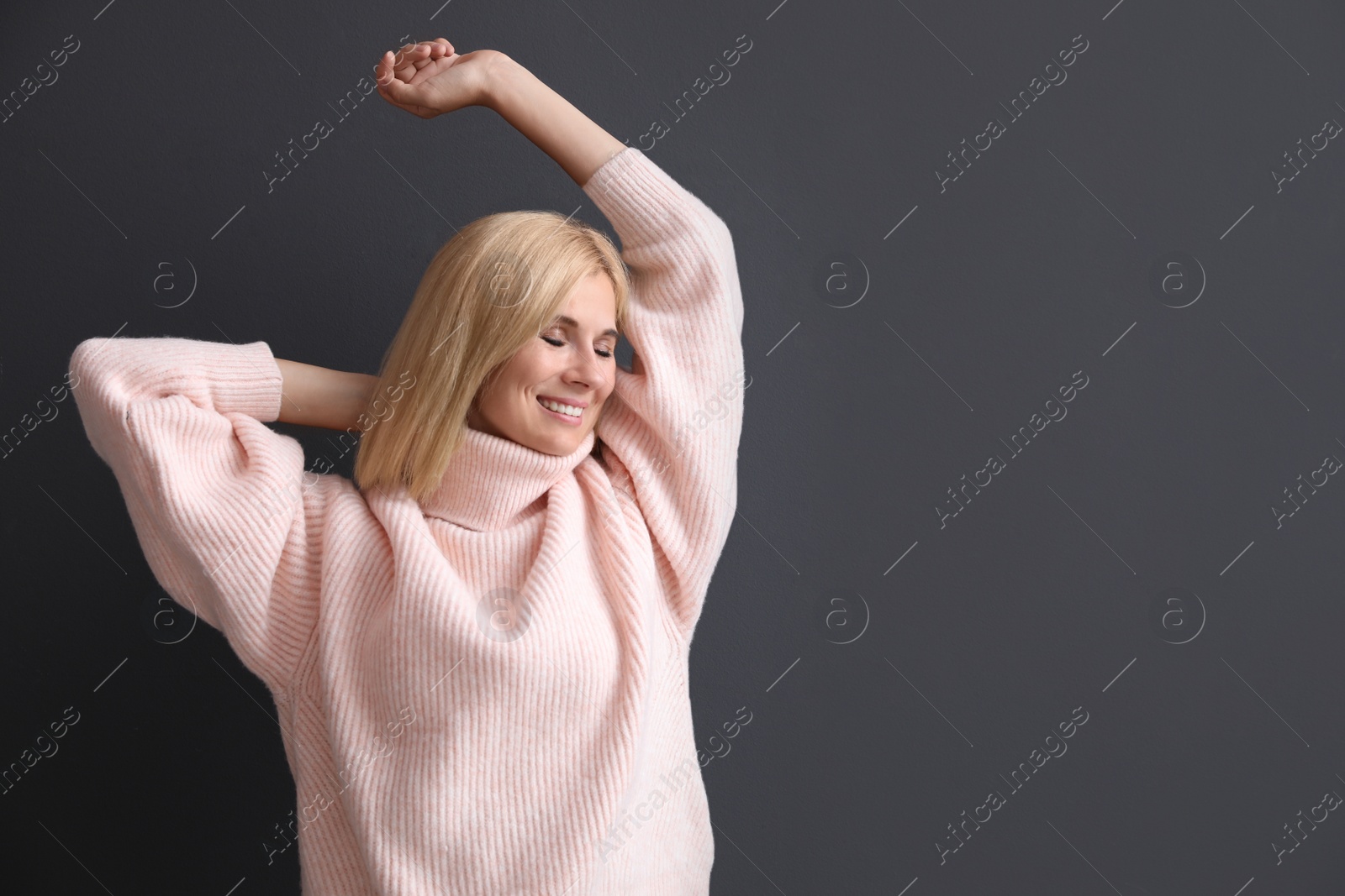 Photo of Happy woman in stylish sweater on black background. Space for text