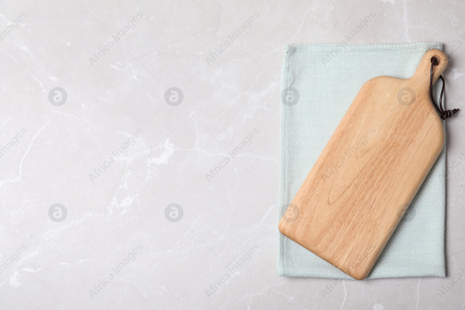 Photo of Fabric napkin with wooden board and space for text on light background, top view