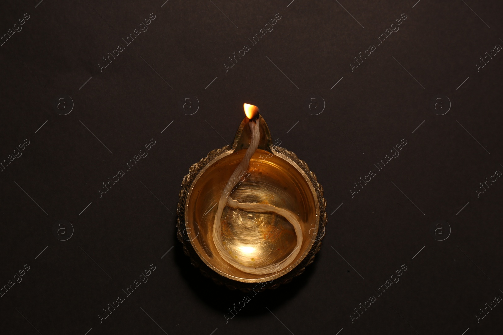 Photo of Lit diya on dark background, top view. Diwali lamp