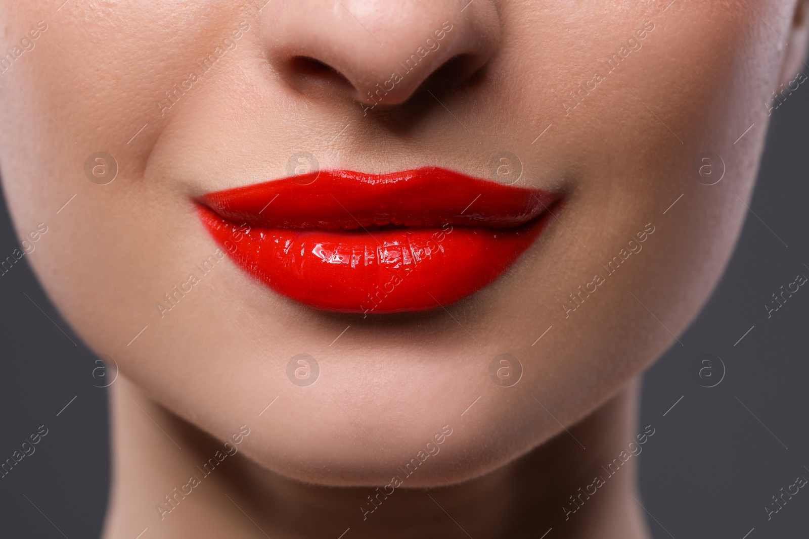 Photo of Young woman with beautiful red lips on grey background, closeup