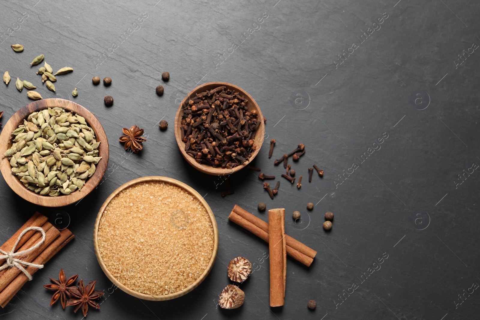 Photo of Different spices in bowls on dark gray textured table, flat lay. Space for text