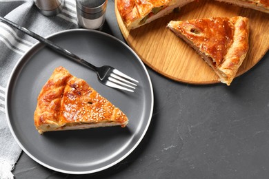 Photo of Tasty homemade pie with filling served on dark grey table, flat lay. Space for text