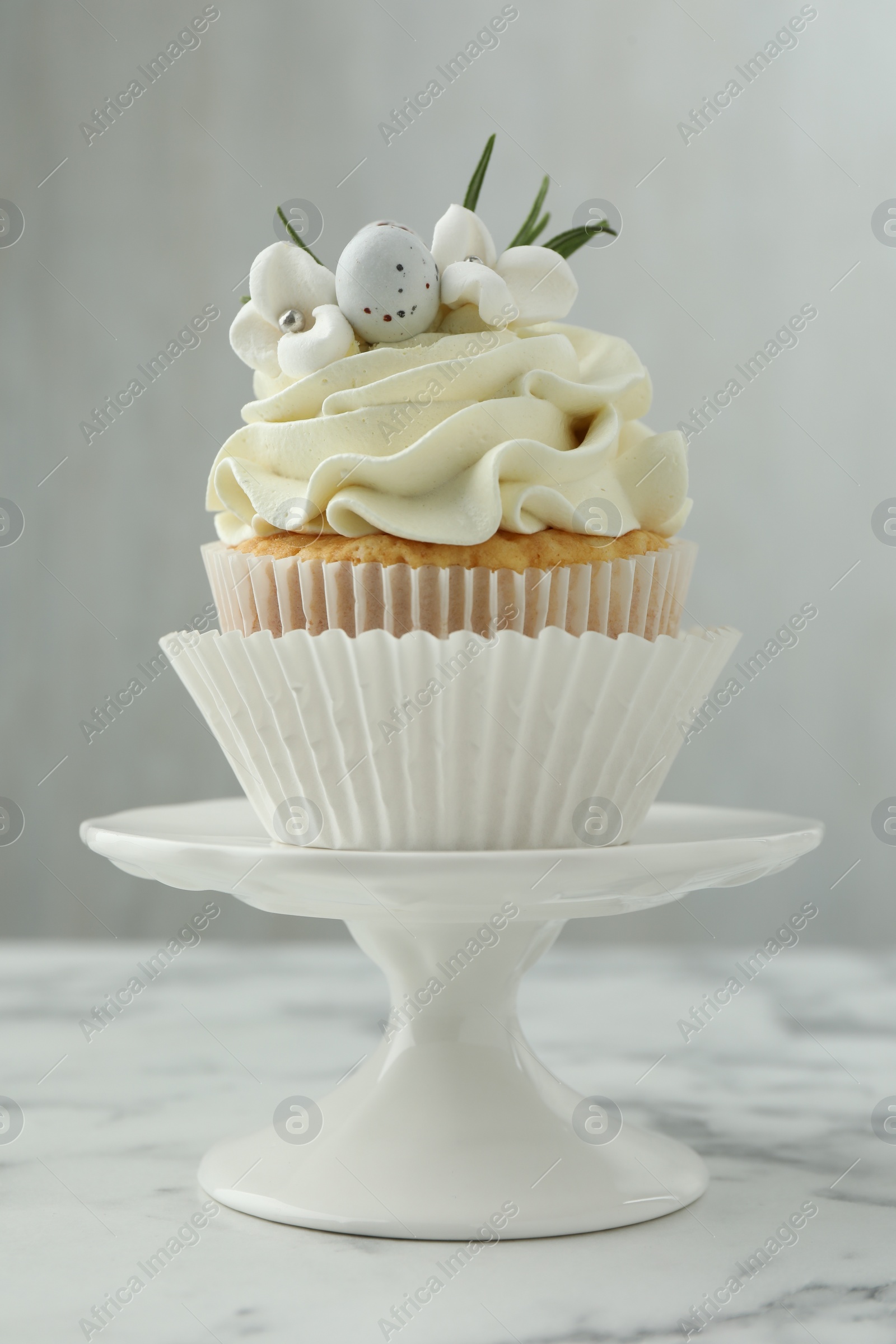 Photo of Tasty Easter cupcake with vanilla cream on white marble table