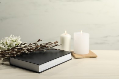 Church candles, Bible, snowdrops and willow branches on white wooden table. Space for text