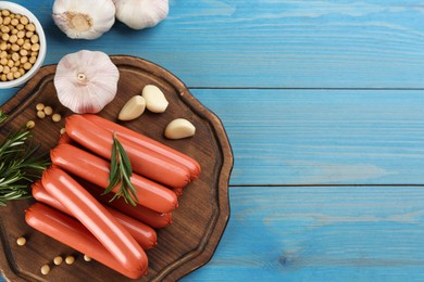 Photo of Fresh raw vegetarian sausages and vegetables on light blue wooden table, flat lay. Space for text