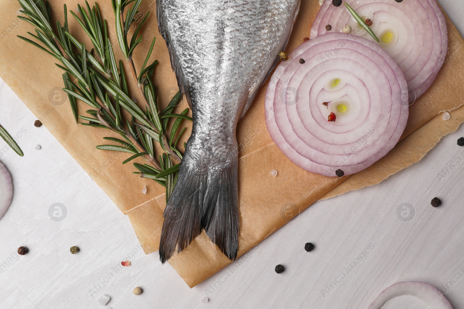 Photo of Raw dorado fish, spices and onion on white wooden table, flat lay