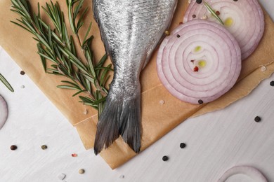 Photo of Raw dorado fish, spices and onion on white wooden table, flat lay