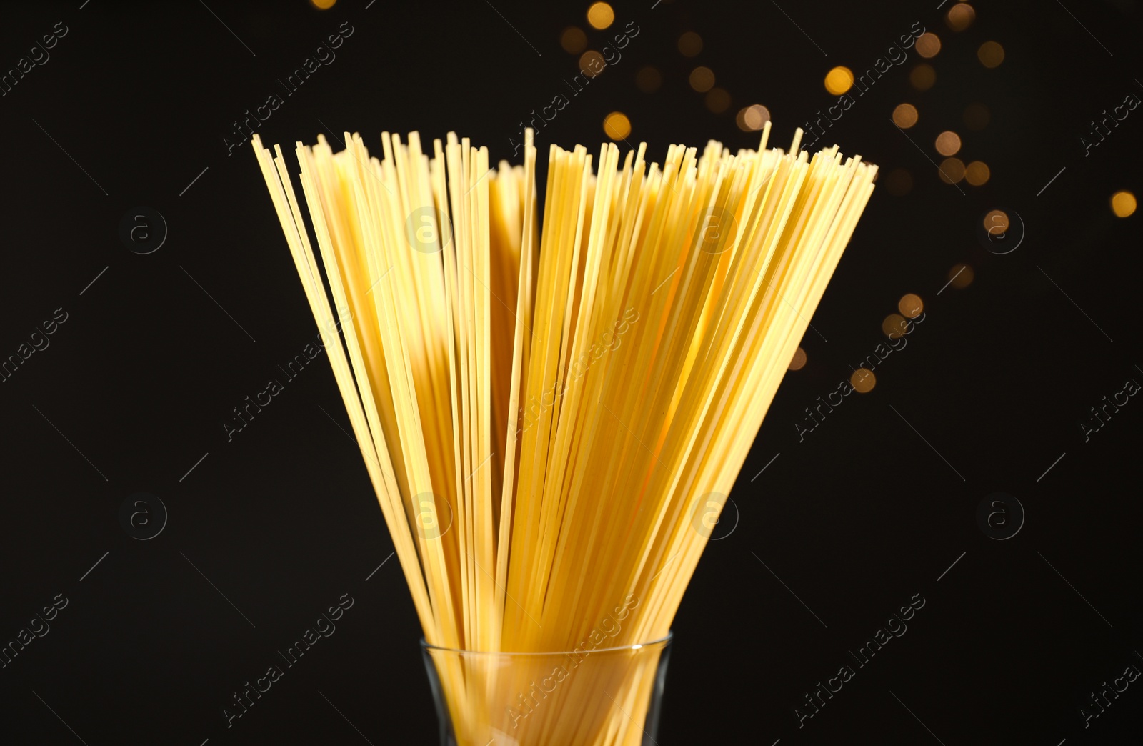 Photo of Uncooked spaghetti against blurred lights, closeup. Italian pasta
