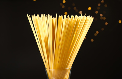 Uncooked spaghetti against blurred lights, closeup. Italian pasta