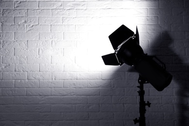 Professional photo studio lighting equipment near brick wall. Space for text