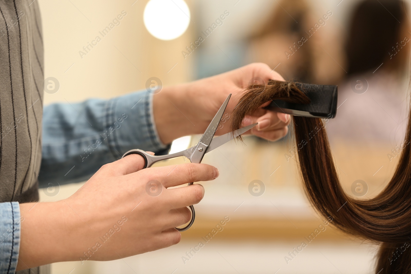 Photo of Barber making stylish haircut with professional scissors in beauty salon, closeup