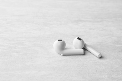 Photo of Pair of modern wireless earphones on light table. Space for text