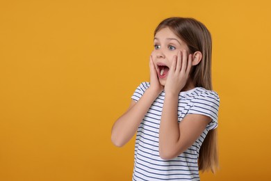 Photo of Portrait of surprised girl on yellow background. Space for text