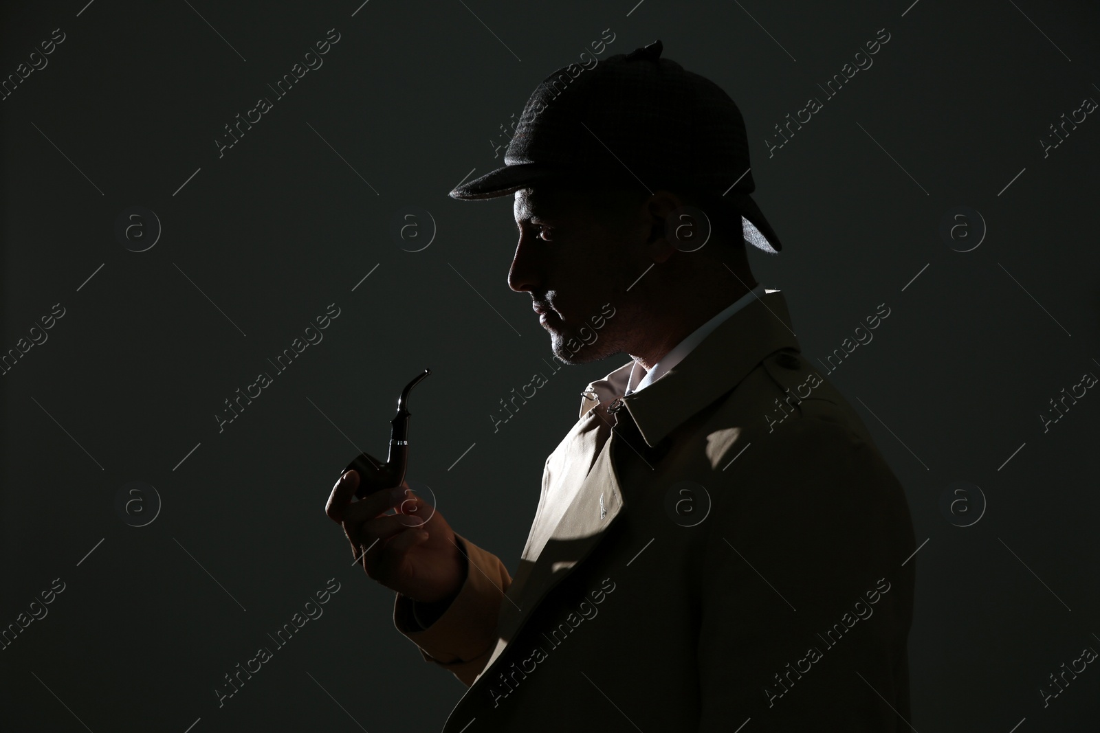 Photo of Old fashioned detective with smoking pipe on dark background