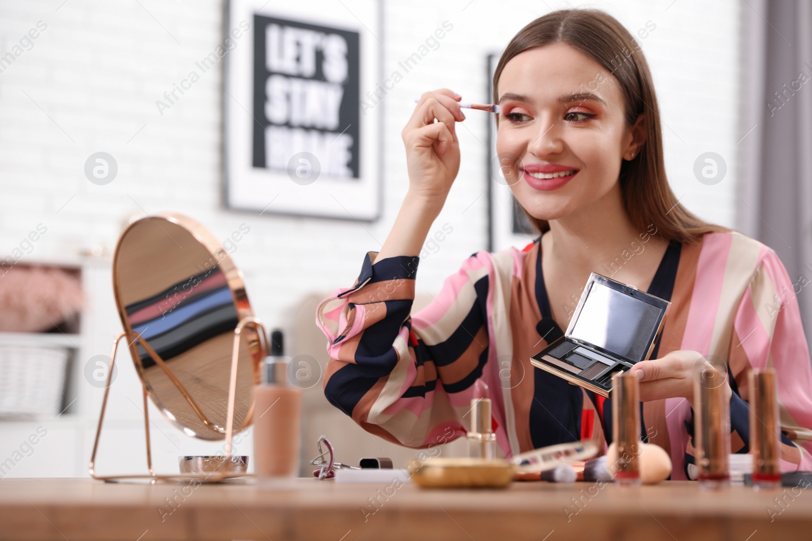 Photo of Young beauty blogger applying eyeshadow at home