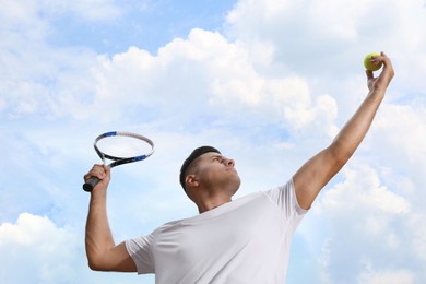Photo of Man serving ball while playing tennis outdoors, low angle view