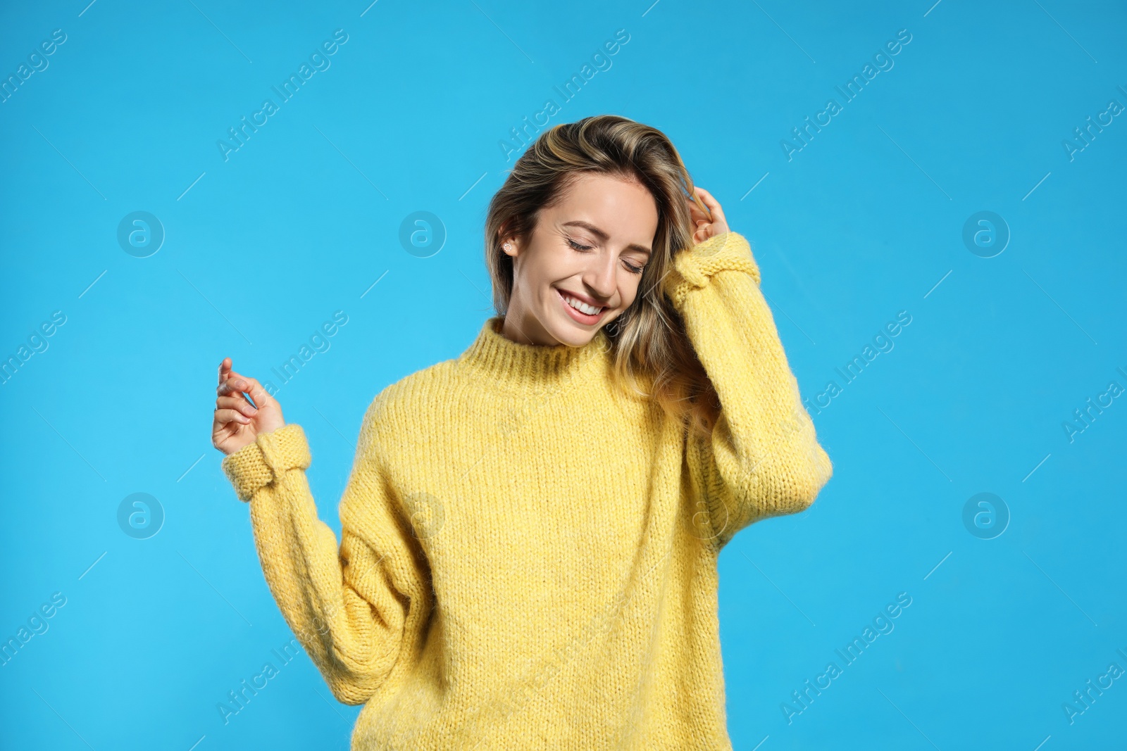 Photo of Beautiful young woman wearing knitted sweater on light blue background