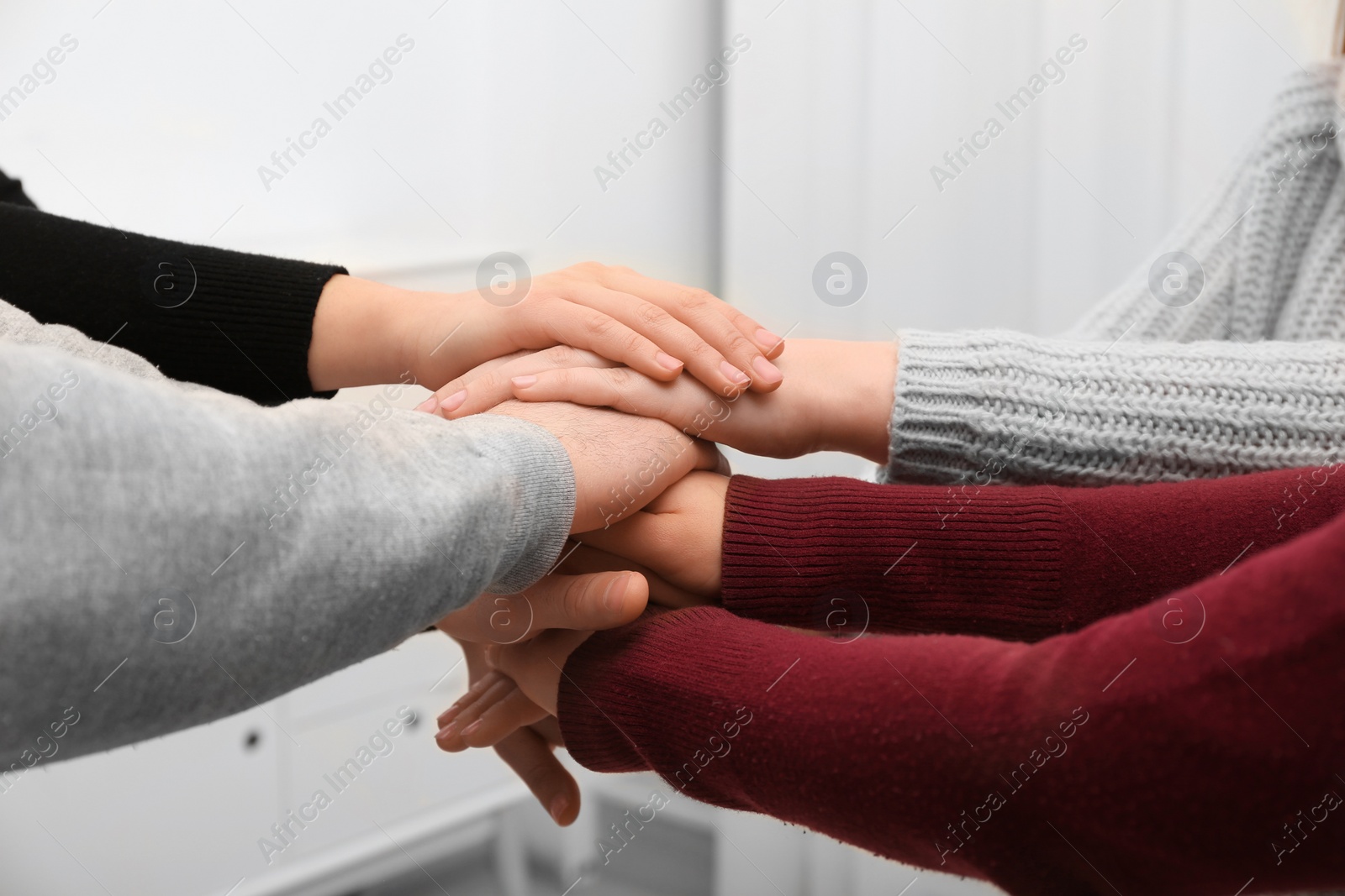 Photo of Young people putting their hands together on blurred background, closeup