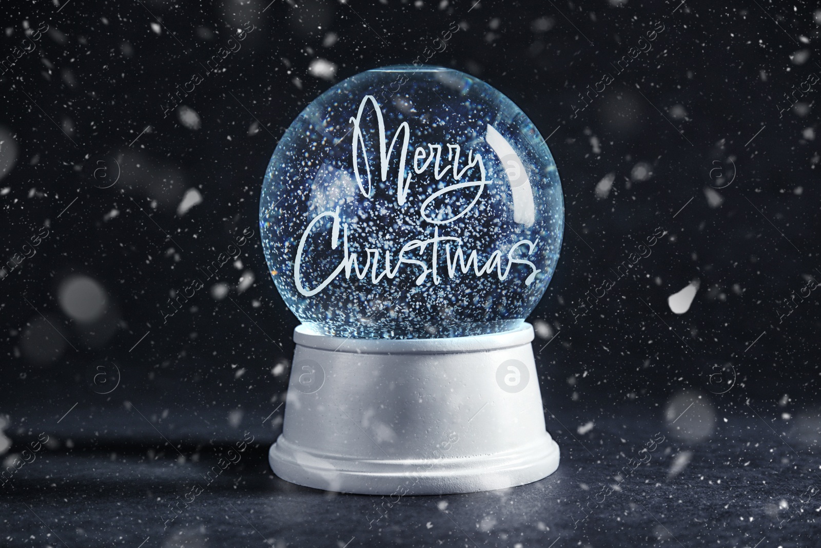 Beautiful snow globe with phrase Merry Christmas on black table Image of Beautiful snow globe with phrase Merry Christmas on black table