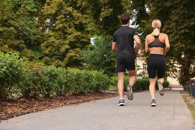 Photo of Healthy lifestyle. Couple running in park, back view with space for text