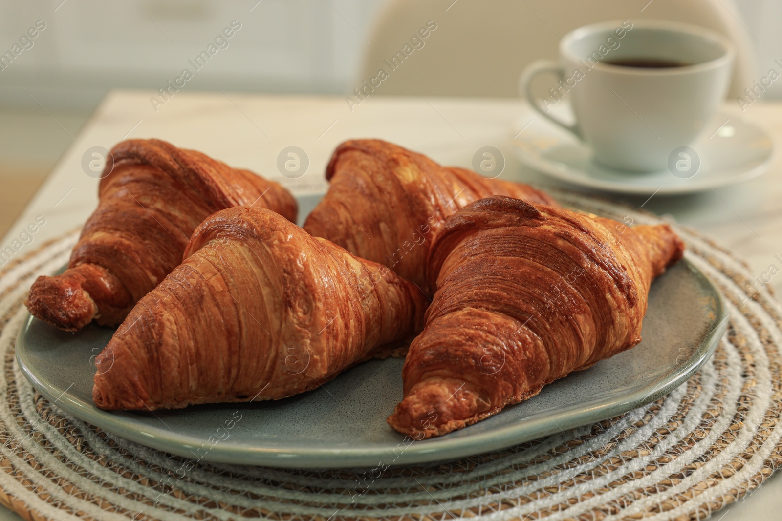 Photo of Tasty croissants and aromatic coffee on table indoors, closeup
