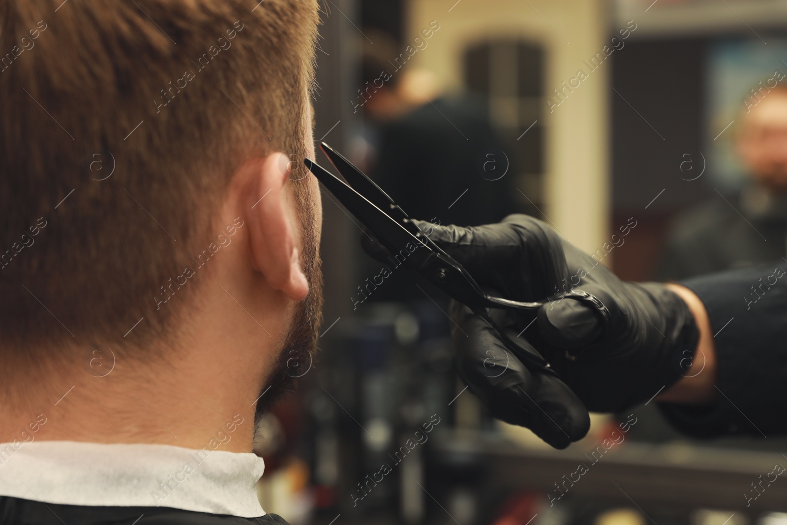Photo of Professional hairdresser working with client in barbershop, closeup 