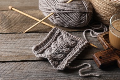 Photo of Soft grey woolen yarn, knitting and needles on wooden table, closeup