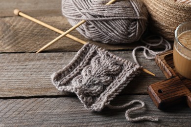 Soft grey woolen yarn, knitting and needles on wooden table, closeup