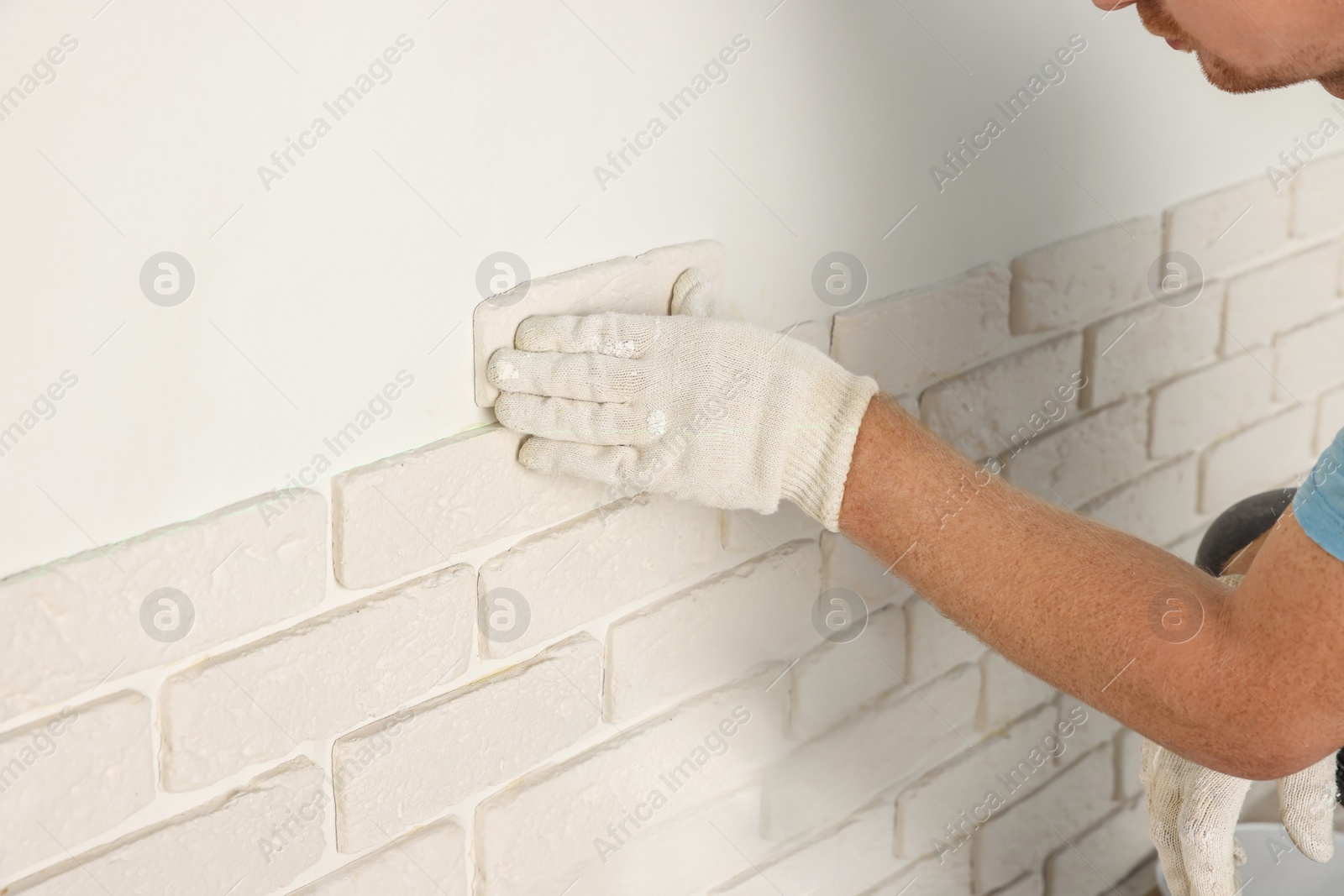 Photo of Worker installing decorative wall tiles in room, closeup