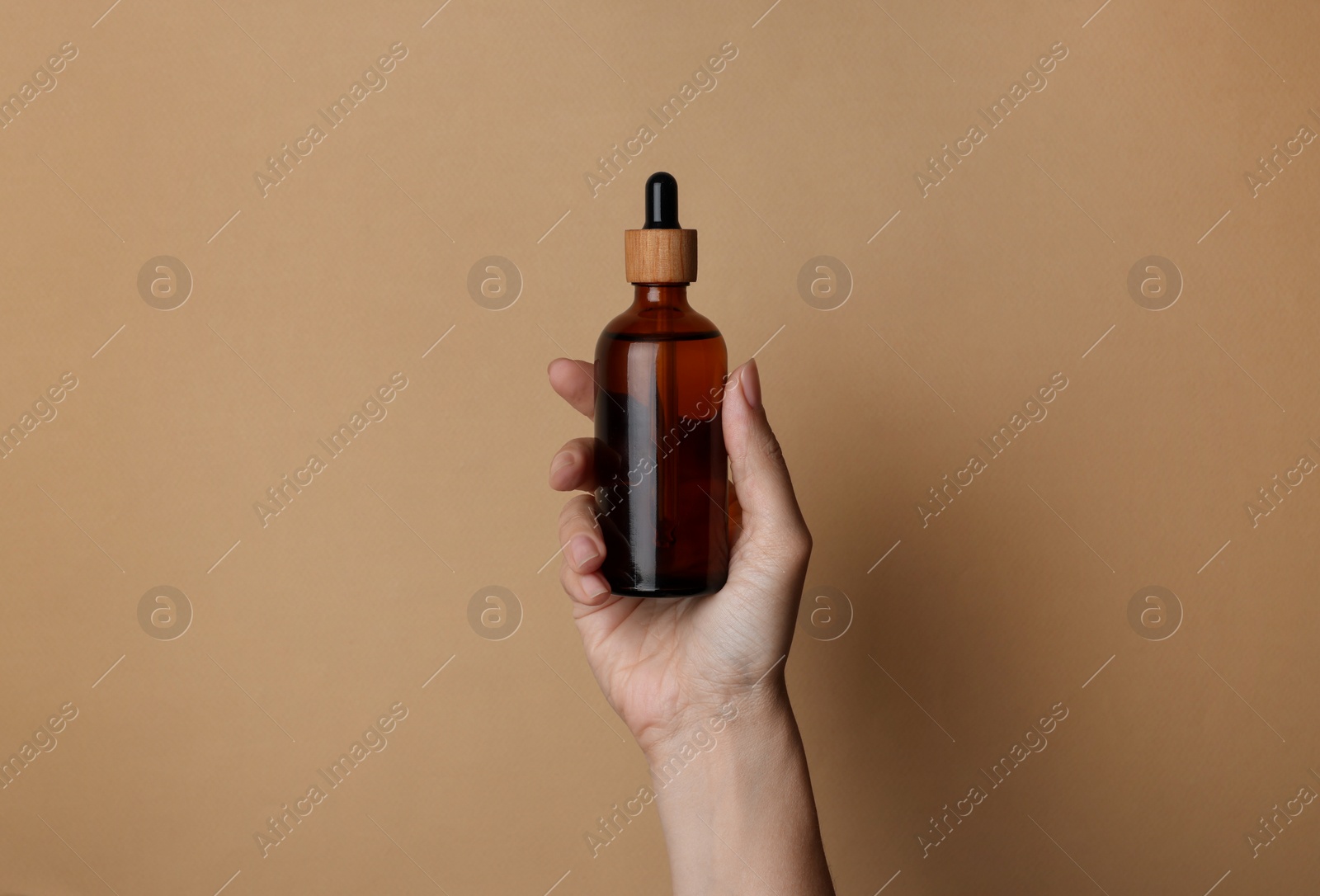 Photo of Woman holding bottle of cosmetic product on beige background, closeup