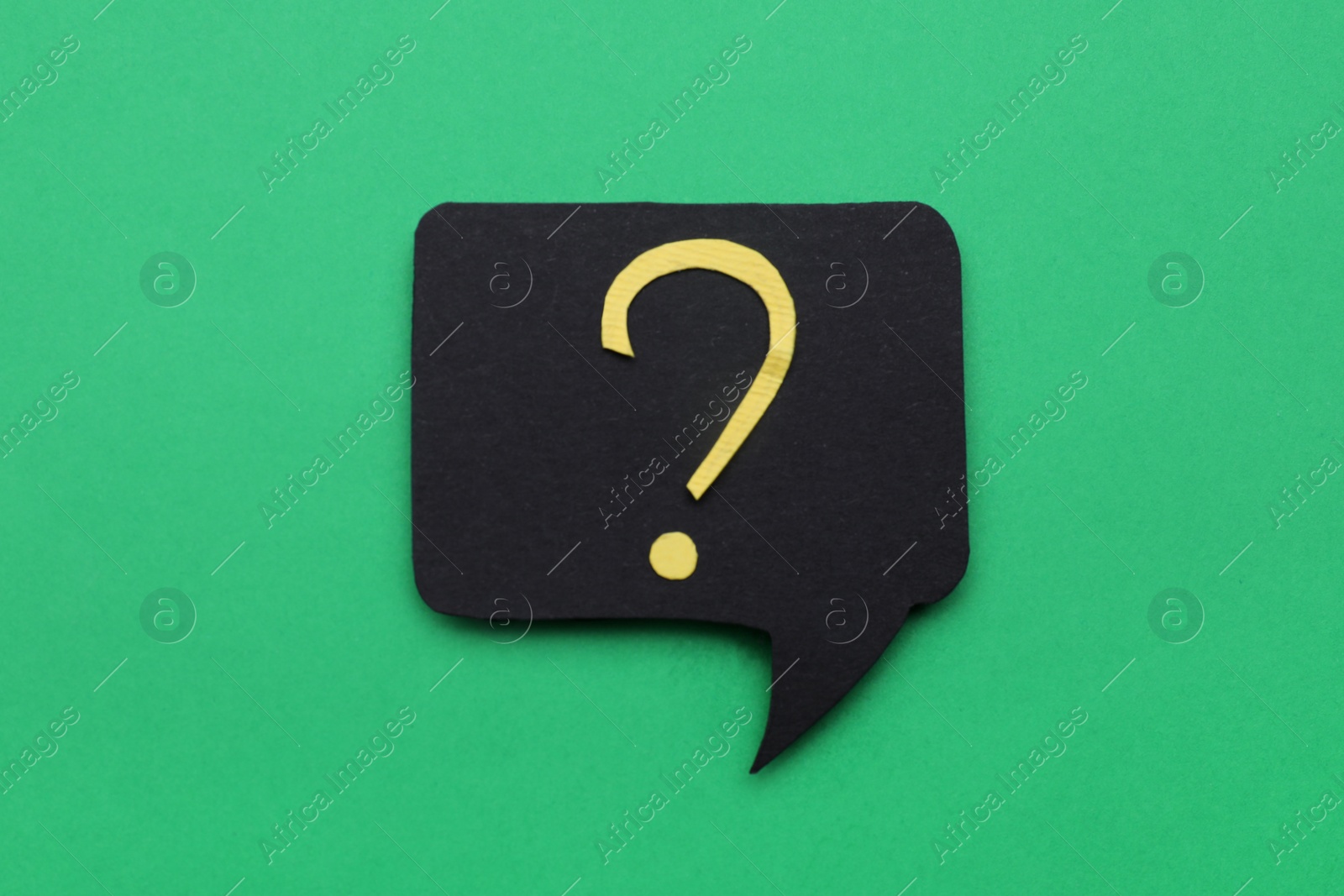 Photo of Paper speech bubble with question mark on green background, top view