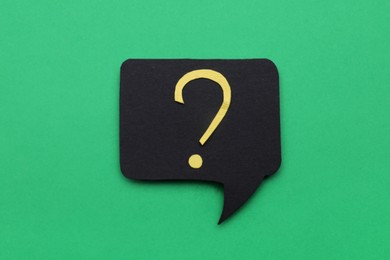 Photo of Paper speech bubble with question mark on green background, top view