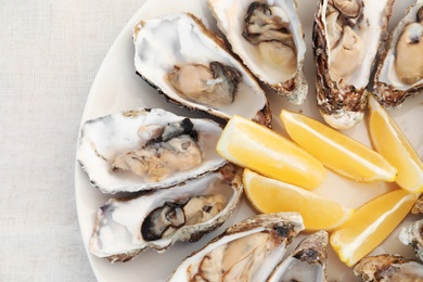 Fresh oysters and cut juicy lemon on plate, top view