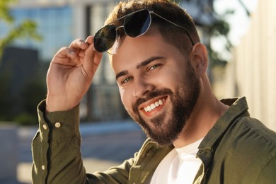 Photo of Handsome smiling man in sunglasses outdoors on sunny day