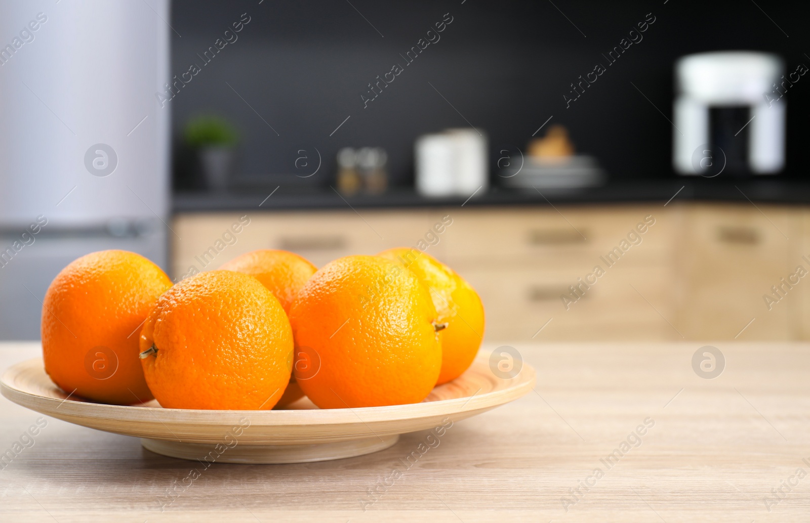 Photo of Fresh oranges on wooden table in kitchen. Space for text