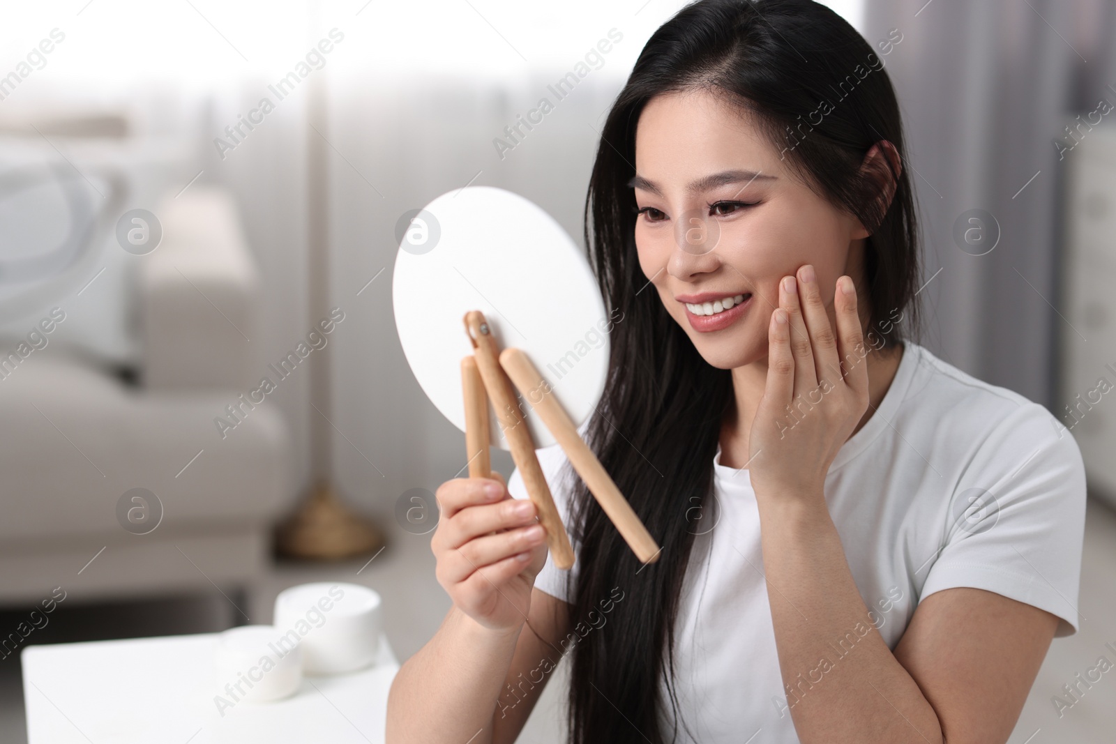 Photo of Woman with perfect skin looking at mirror indoors, space for text