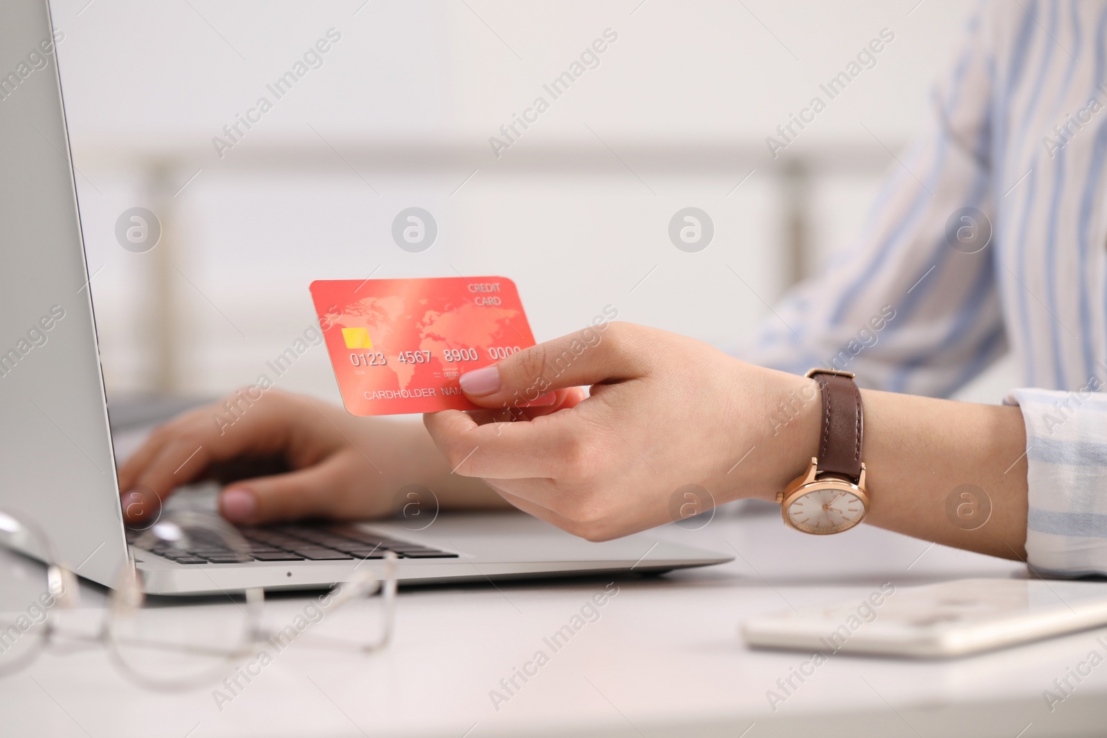 Photo of Woman with credit card using laptop for online shopping at white table, closeup