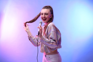 Emotional woman with microphone singing in color lights