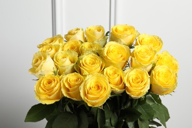 Beautiful bouquet of yellow roses near white wall, closeup