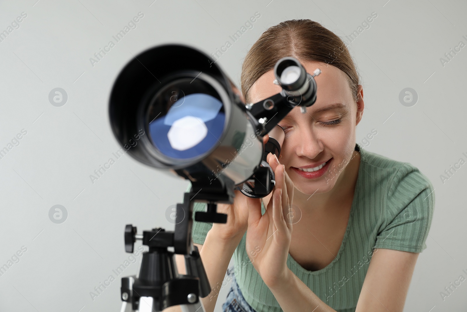 Photo of Young astronomer looking at stars through telescope on grey background