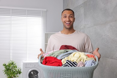 Emotional man with basket full of laundry in bathroom. Space for text