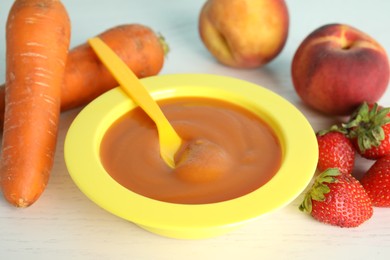 Photo of Baby food in bowl and fresh ingredients on white wooden table