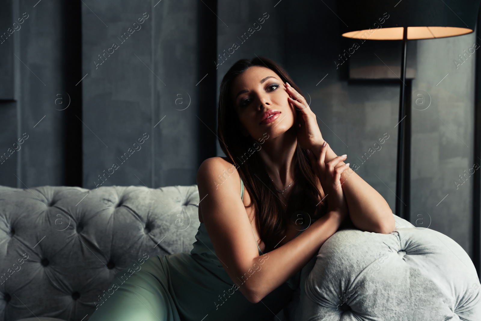 Photo of Beautiful woman in elegant dress on sofa indoors. Luxury lifestyle