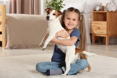 Photo of Cute girl hugging her dog on floor at home. Adorable pet