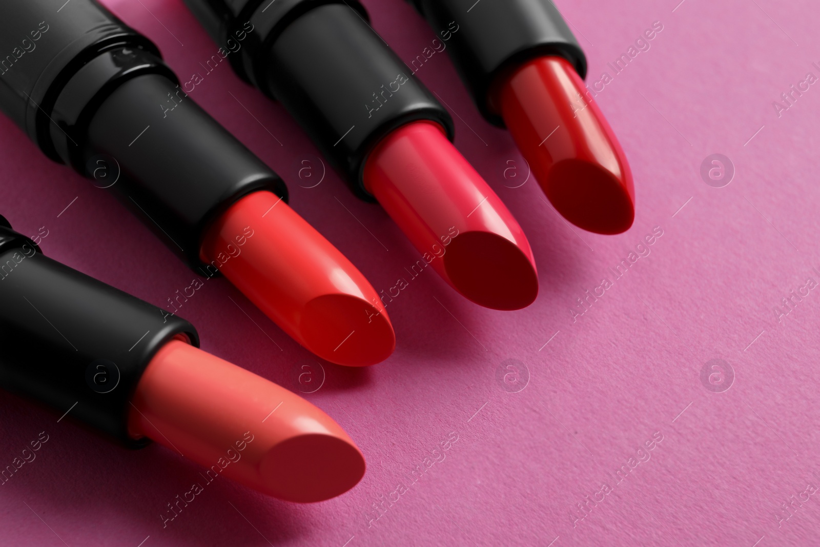 Photo of Different beautiful glossy lipsticks on pink background