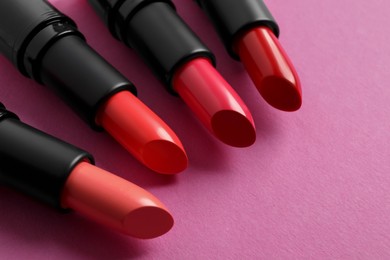 Photo of Different beautiful glossy lipsticks on pink background