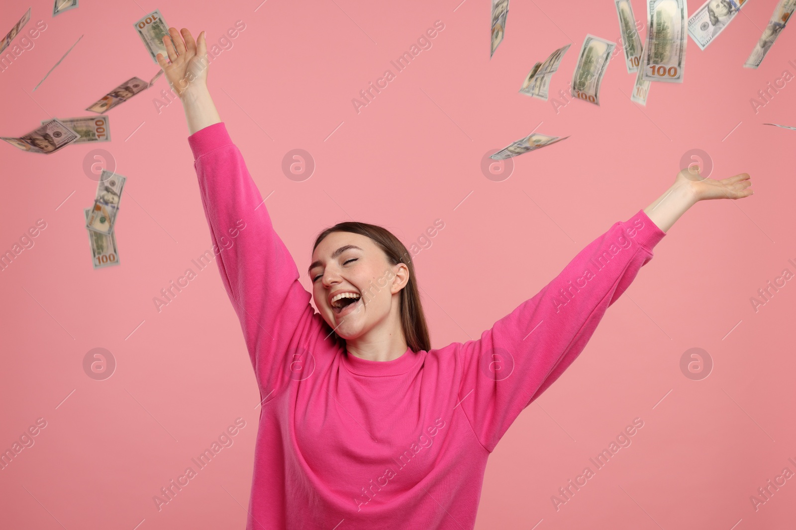 Photo of Happy woman under money shower on pink background